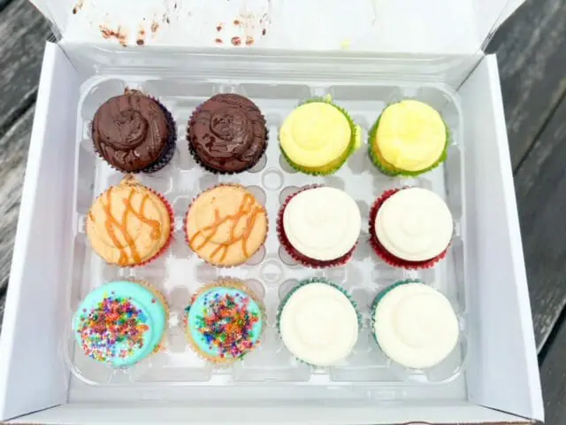 assorted cupcakes in box open lid-cupcake by design cupcakes and cupcake toppers reviews-mealfinds